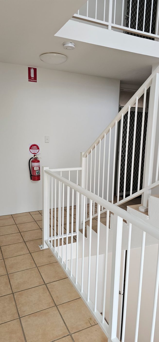 Repainted white stairwell landing with a white balustrade and handrail